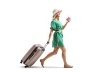 From Airport Gates to Dinner Dates: One-Day, One-Bag Living Young woman in a green dress pulling a suitcase and holding a passport
