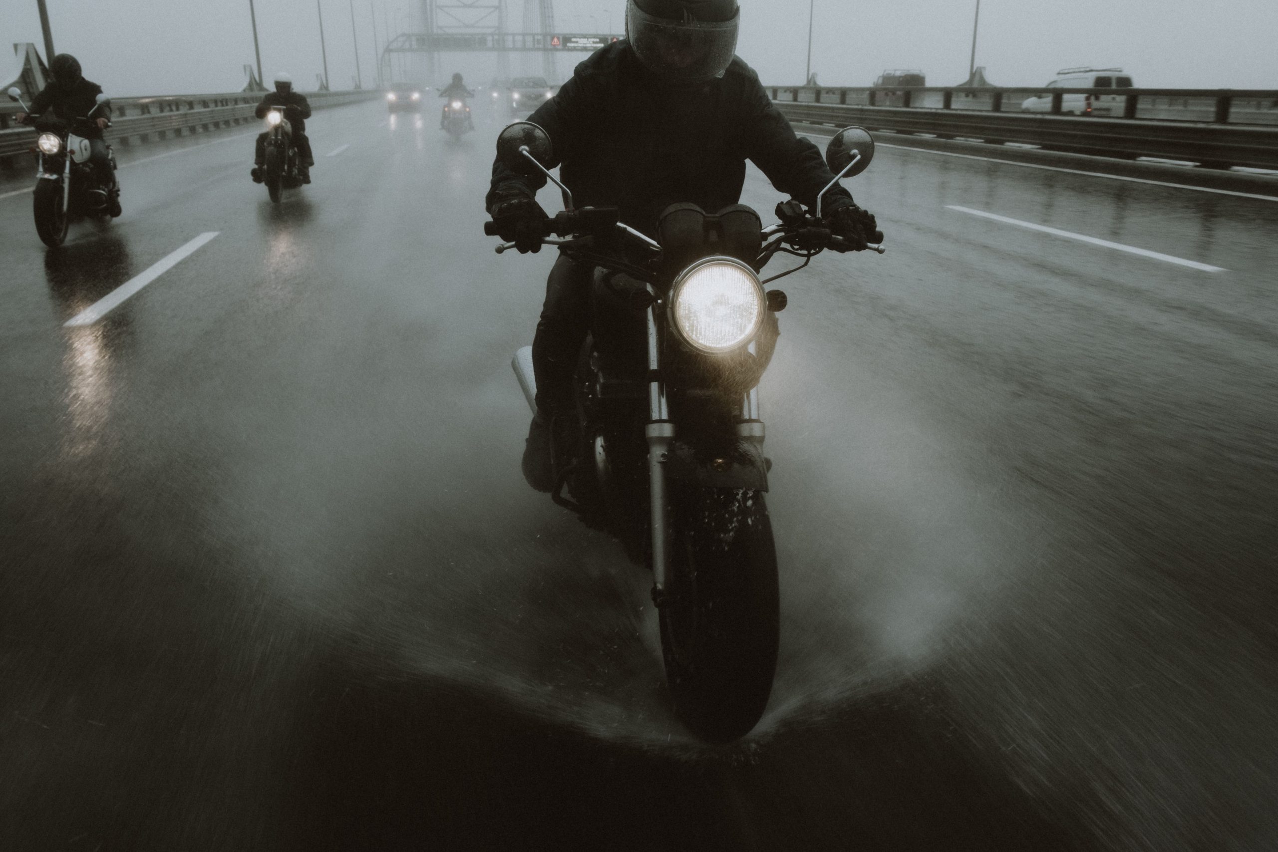 motorcycle-riding-heavy-rain-highway Group of motorcyclists riding through heavy rain on a highway with water splashing around them