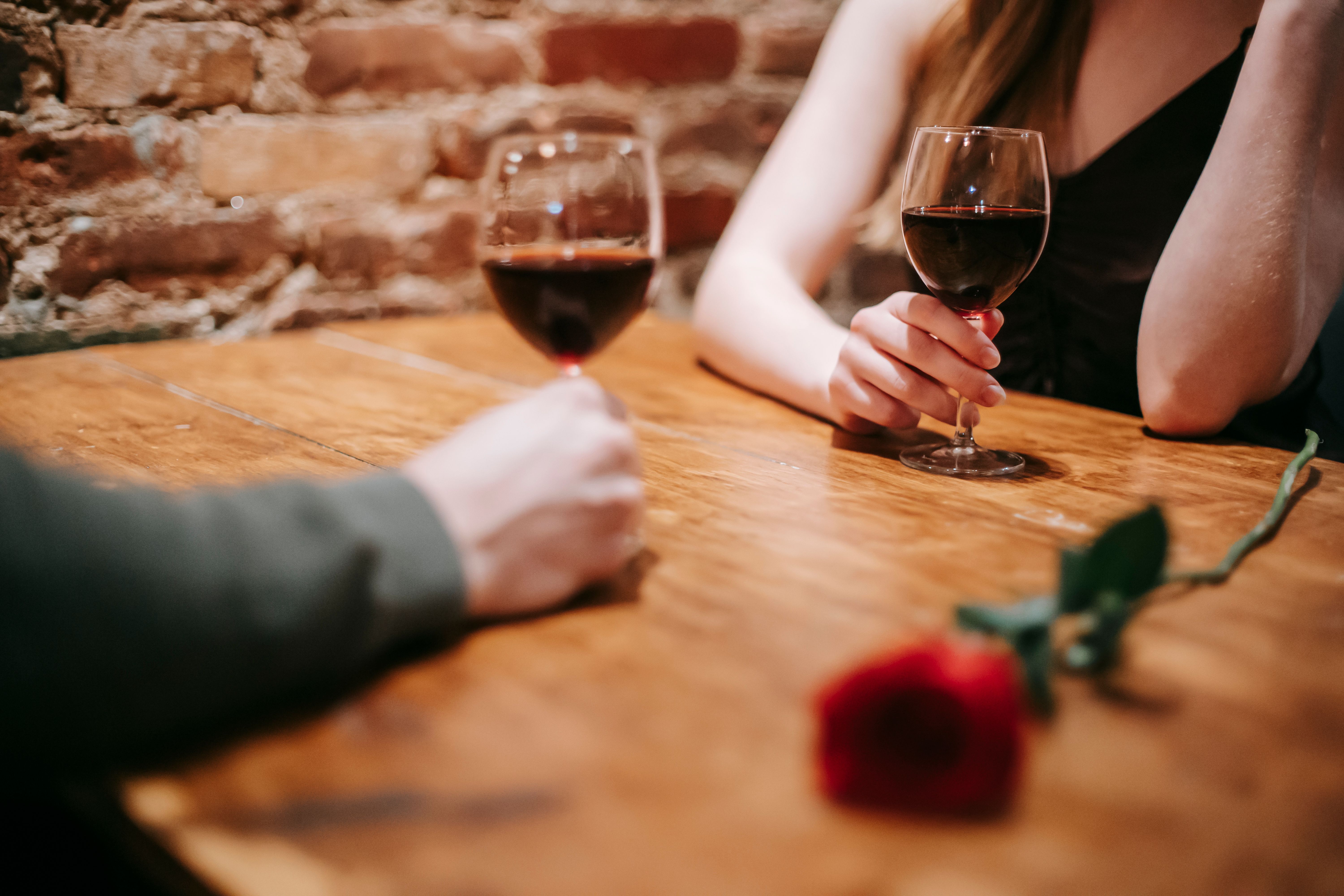 An elegantly dressed couple sharing wine during an intimate restaurant date