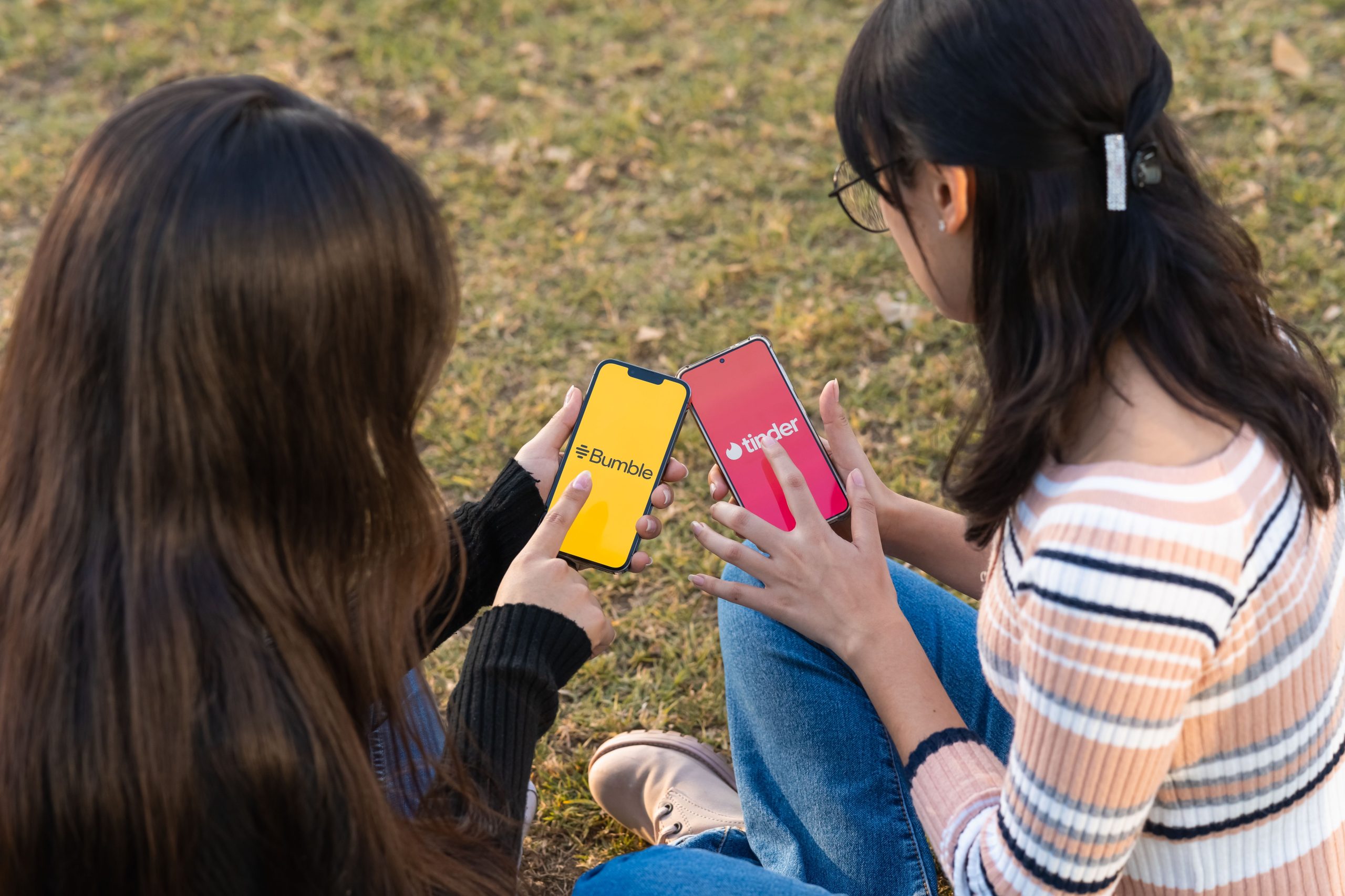 modern-dating-apps-smartphones Two women using dating apps on smartphones outdoors, representing modern dating alternatives